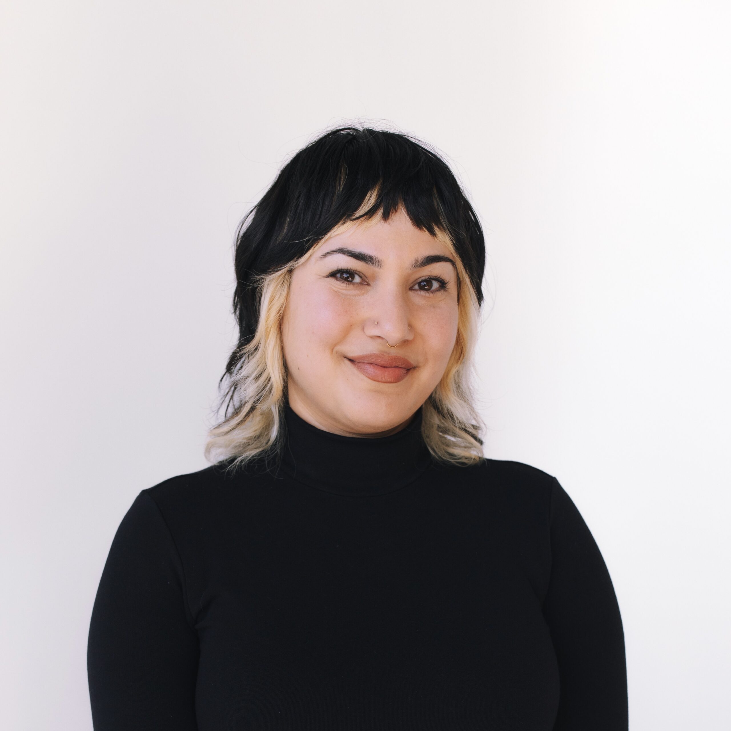 Headshot of Neda wearing a black mockneck against a white background