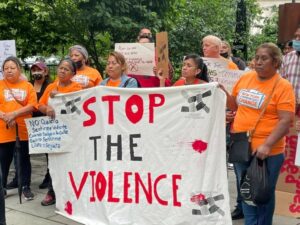 Organizers in orange shirts holding a banner with the text 'Stop the Violence'