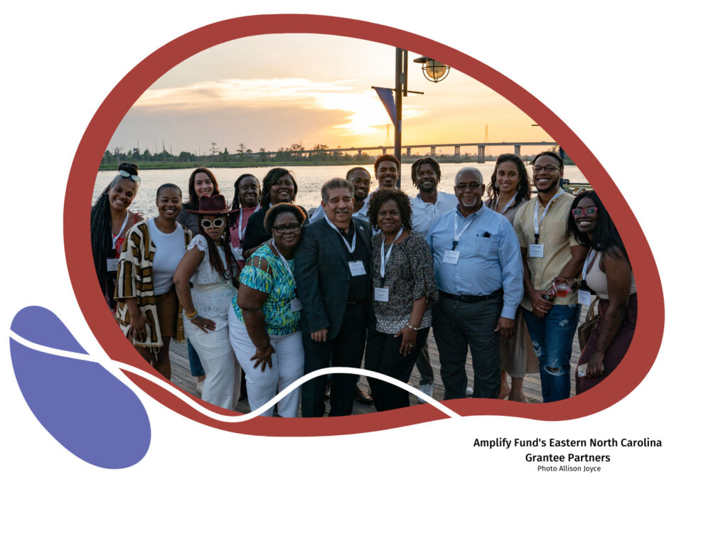 Group photo of Amplify Fund's Eastern NC grantee partners and Melody Baker. The image has a dark red background and there is a purple organic shape in the lower right-hand corner.