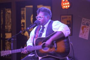 Image of Crys Matthews singing and playing the guitar.