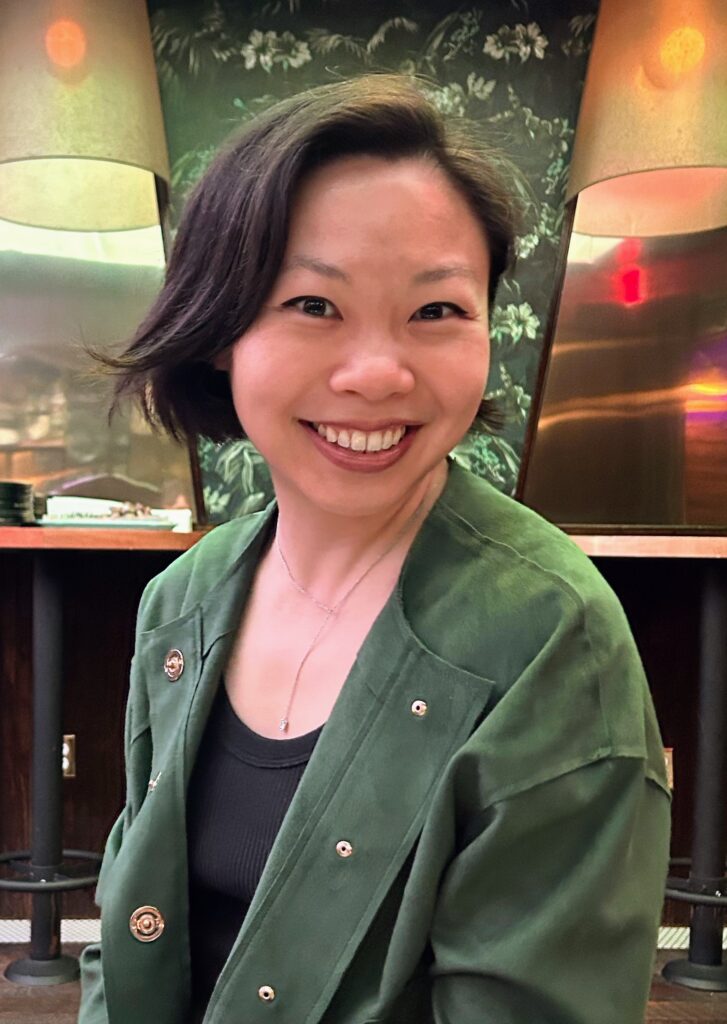 Headshot for Stephanie Chan. Stephanie is wearing a black shirt underneath a green jacket.