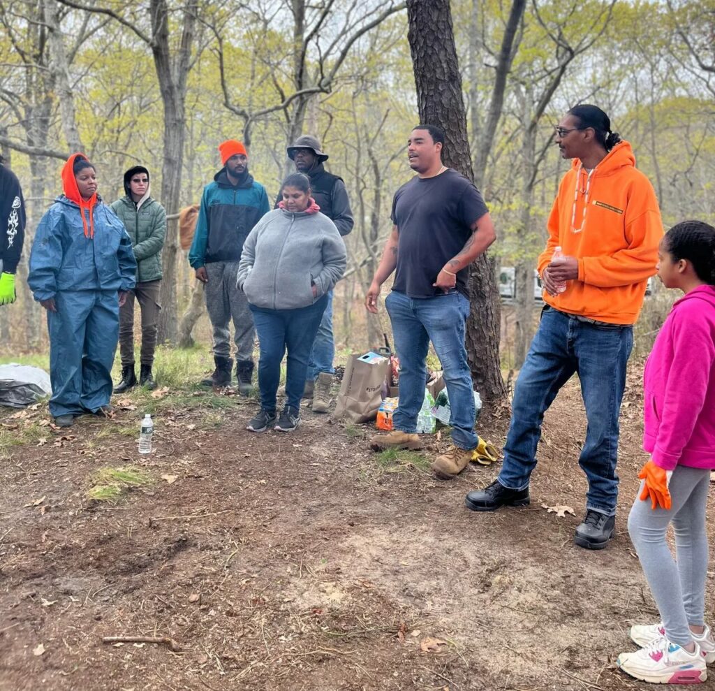Photo of a group of people cleaning ceremonial grounds on Shinnecock territory.